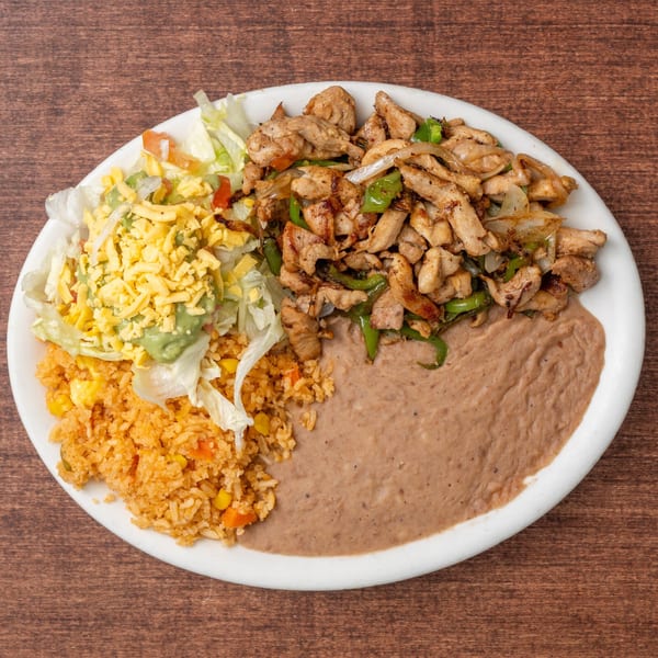 A plate of chicken fajitas with rice, refried beans, and a salad topped with cheese and guacamole.