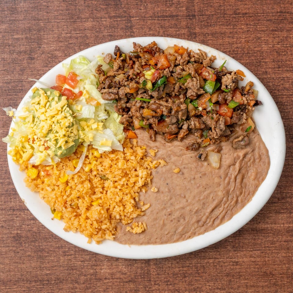 A white plate with ground beef, rice, refried beans, and a salad with guacamole and cheese.