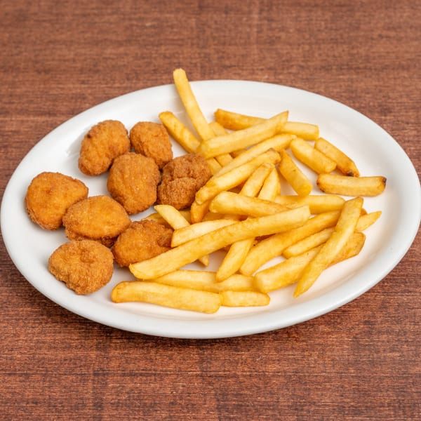 A white plate filled with golden-brown chicken nuggets and crispy french fries on a wooden table.