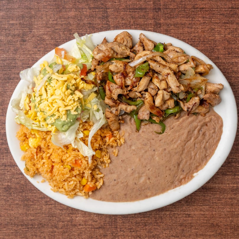 Chicken fajitas with rice, refried beans, and a side salad with guacamole and shredded cheese.