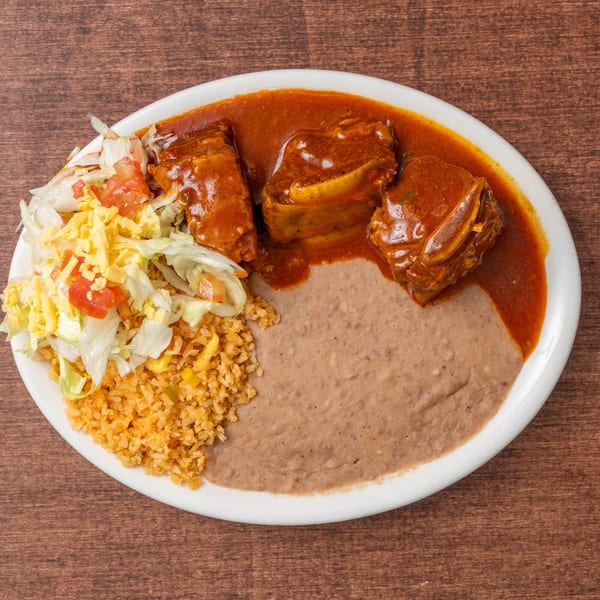 A plate of Mexican food with chile colorado, rice, refried beans, and a side salad.